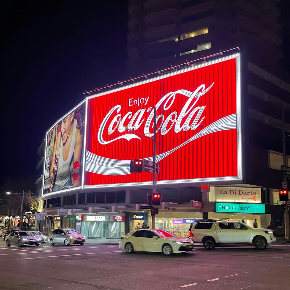 Illuminated billboard glowing red over an evening street
